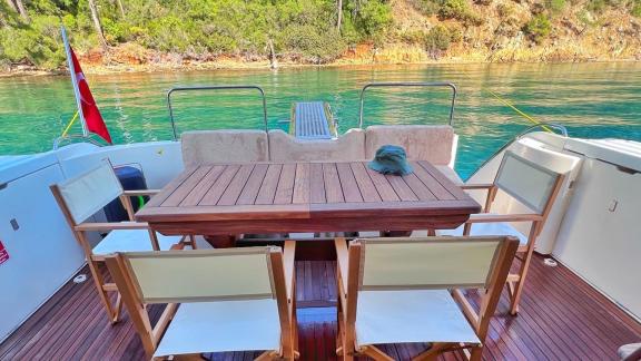 The aft deck seating area of the motor yacht Hadron is equipped with a table and chairs.